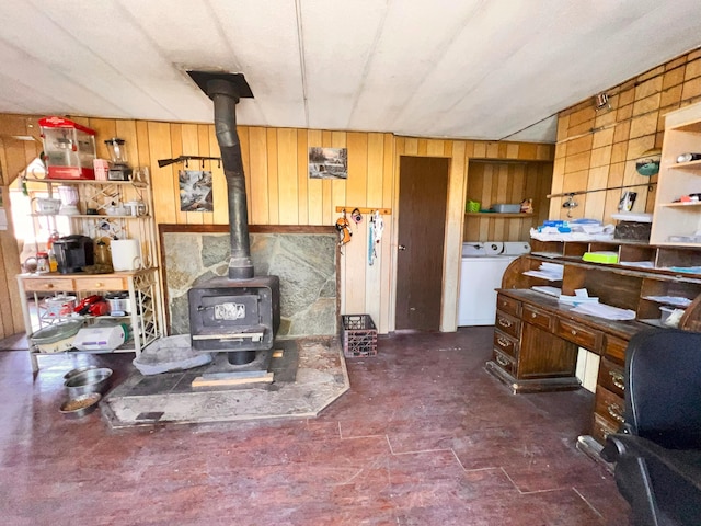 interior space with a wood stove, washer / dryer, and wooden walls