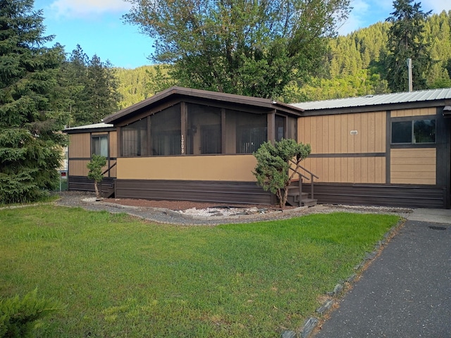1208 Overlook Blvd, Marcus, WA 99151 - view of side of home with a yard, a view of trees, a sunroom, and metal roof