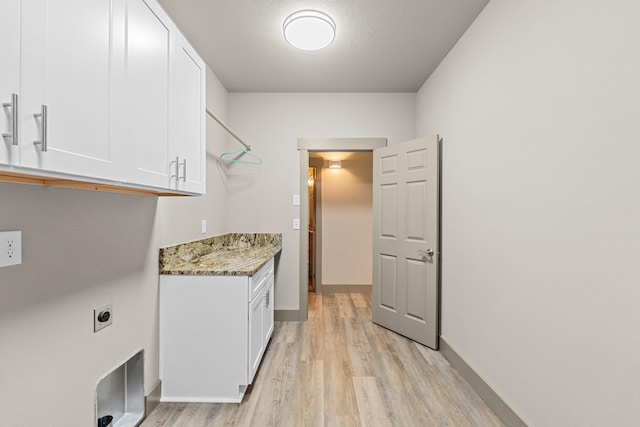 231 Hogans Way, Chewelah, WA 99109 - washroom with electric dryer hookup, light wood-style flooring, cabinet space, and a textured ceiling