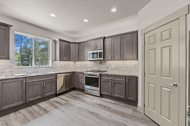 231 Hogans Way, Chewelah, WA 99109 - kitchen with stainless steel appliances, dark brown cabinetry, light stone countertops, backsplash, and recessed lighting