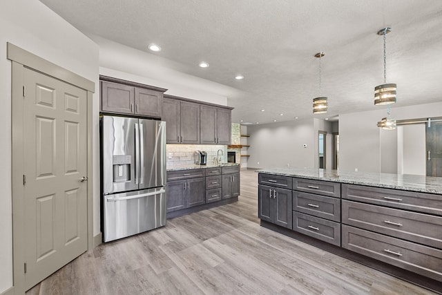231 Hogans Way, Chewelah, WA 99109 - kitchen with stainless steel fridge, recessed lighting, decorative backsplash, dark brown cabinetry, and light wood-style flooring