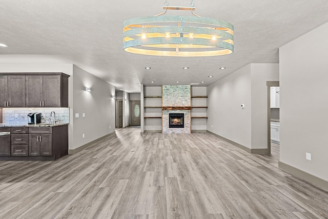 231 Hogans Way, Chewelah, WA 99109 - unfurnished living room featuring light wood-style flooring, a textured ceiling, a fireplace, and recessed lighting