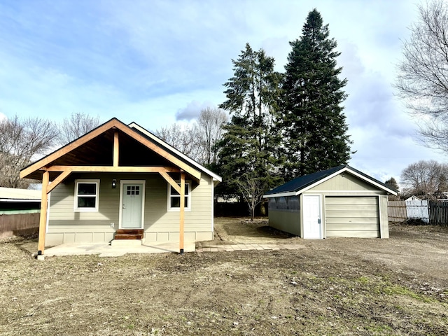 view of front of home featuring a garage, an outbuilding, driveway, and fence