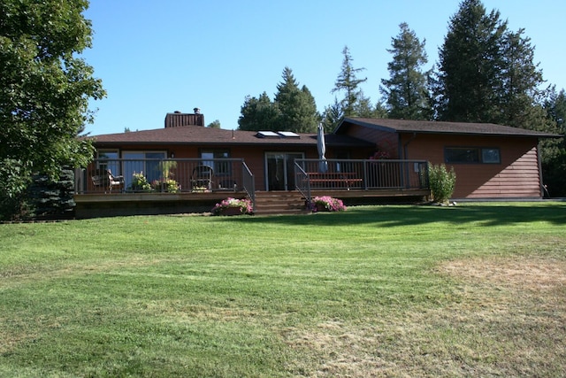 rear view of house with a lawn and a wooden deck