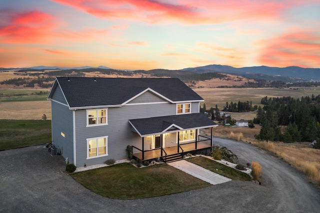 view of front of property with a mountain view, central AC, a yard, and covered porch