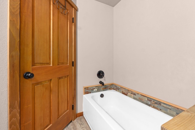 bathroom with a garden tub and wood finished floors