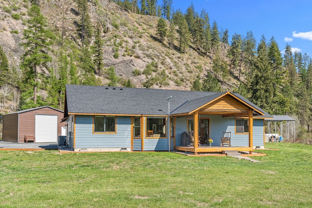 ranch-style home featuring an outdoor structure, a deck, a front yard, central air condition unit, and a detached garage