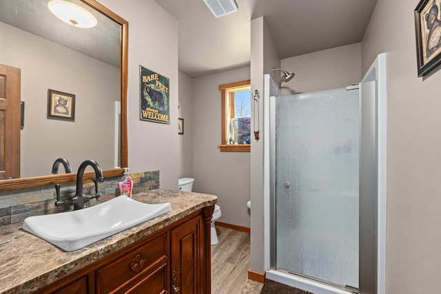 bathroom featuring vanity, toilet, wood finished floors, visible vents, and a stall shower