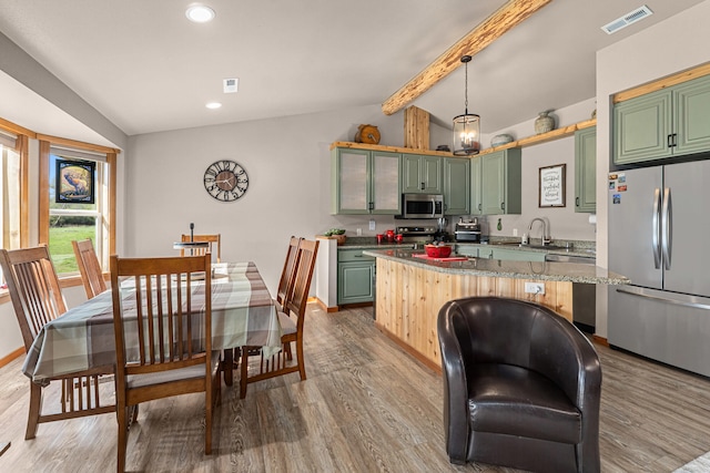 kitchen featuring appliances with stainless steel finishes, light wood-style flooring, vaulted ceiling with beams, visible vents, and green cabinets