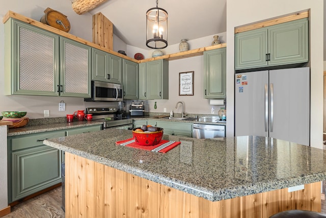 kitchen featuring wood finished floors, stone countertops, lofted ceiling with beams, a sink, and stainless steel appliances