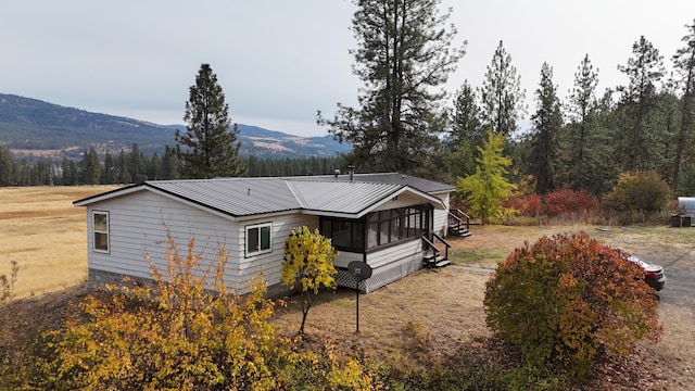 back of house with a mountain view, metal roof, and a forest view