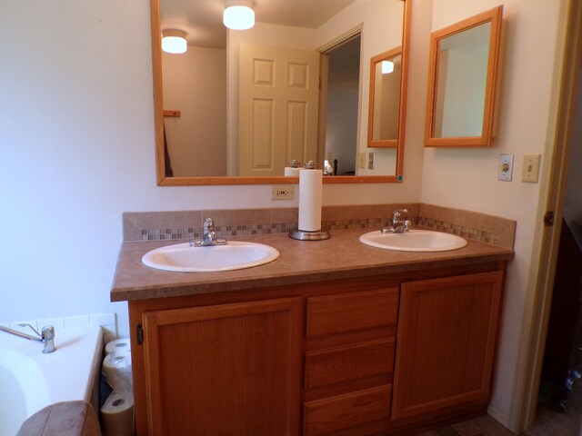 bathroom with double vanity, a bath, and a sink