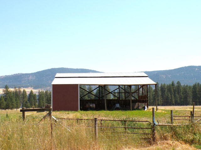 view of pole building featuring a mountain view, a view of trees, a rural view, and fence