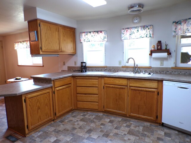 kitchen with a sink, a peninsula, a wealth of natural light, and white dishwasher