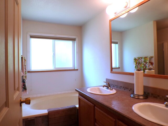 full bath featuring a garden tub, double vanity, and a sink