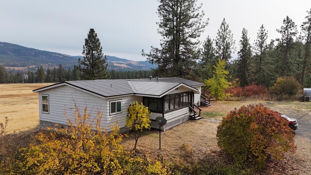 rear view of property featuring metal roof, a wooded view, and a mountain view