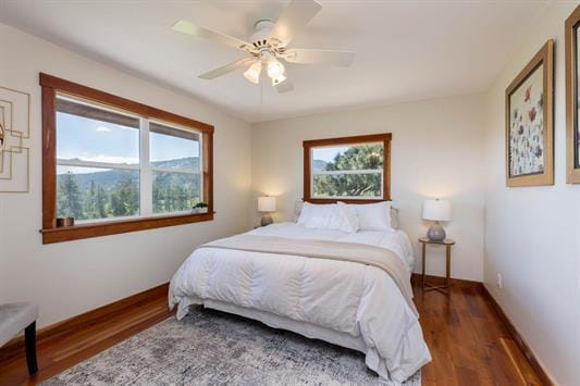 bedroom with ceiling fan, wood finished floors, and baseboards