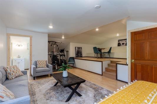 living area with light wood-type flooring, vaulted ceiling, and recessed lighting