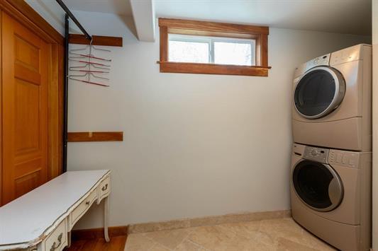 laundry area with stacked washer / drying machine, laundry area, and baseboards