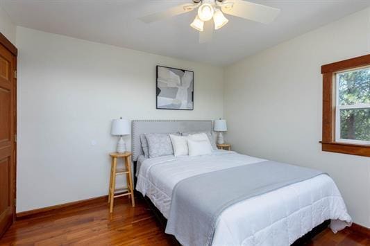 bedroom featuring a ceiling fan, baseboards, and wood finished floors