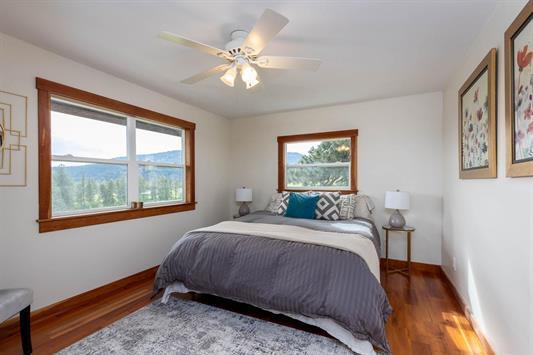 bedroom featuring multiple windows, ceiling fan, baseboards, and wood finished floors