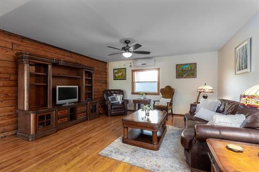 living room with ceiling fan, a wall mounted AC, and wood finished floors