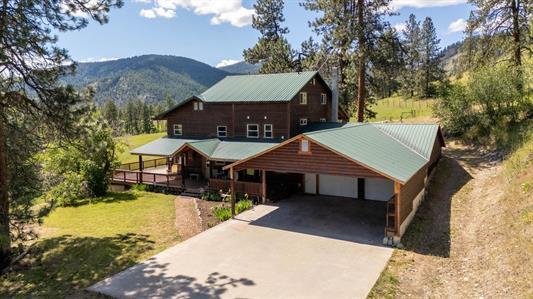 rustic home with a garage, concrete driveway, a front lawn, and a mountain view