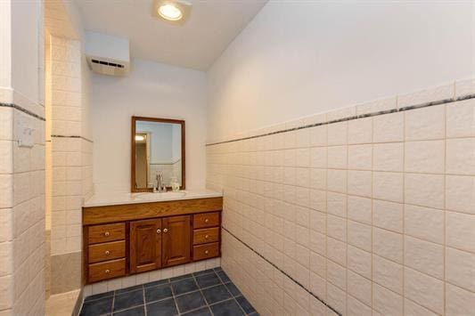 bathroom featuring a wainscoted wall, a wall unit AC, tile walls, vanity, and tile patterned flooring