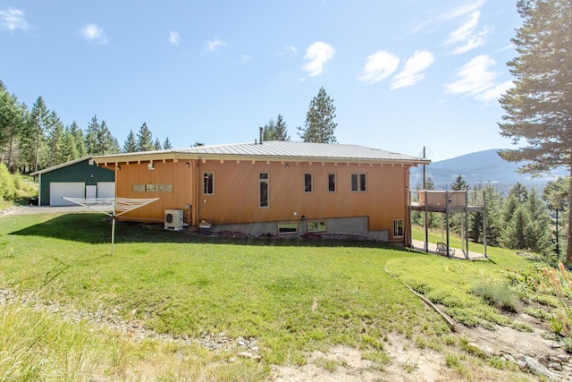 rear view of property with a mountain view, metal roof, a lawn, and an outdoor structure