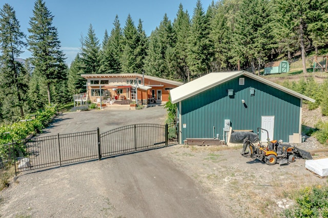 view of outdoor structure featuring an outbuilding, driveway, fence, and a gate