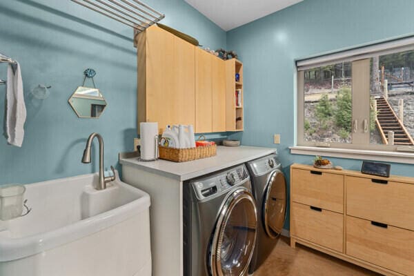 clothes washing area with washing machine and clothes dryer, a sink, and cabinet space