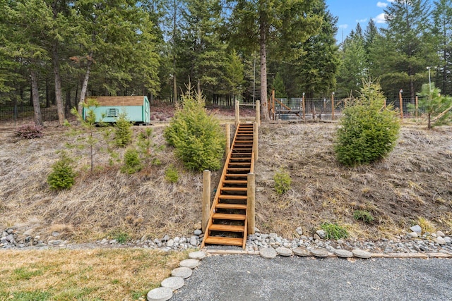 view of yard featuring an outbuilding, a shed, stairs, and fence