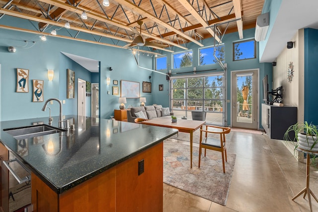 kitchen with finished concrete floors, a high ceiling, a sink, and an island with sink