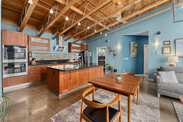 kitchen featuring dark countertops, appliances with stainless steel finishes, open floor plan, a kitchen island with sink, and concrete flooring