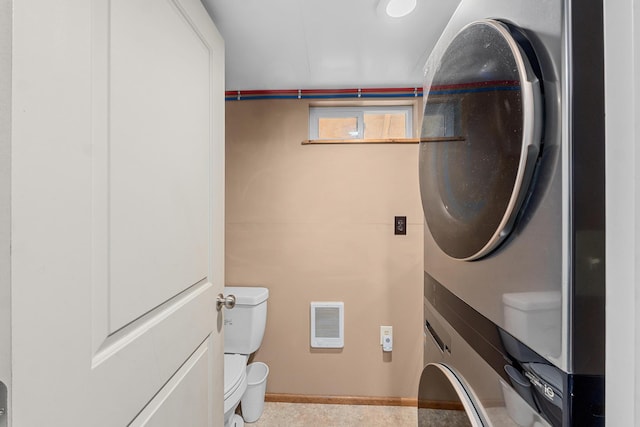 laundry area with stacked washing maching and dryer and heating unit