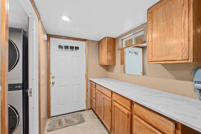 kitchen featuring stacked washer and clothes dryer and light stone countertops