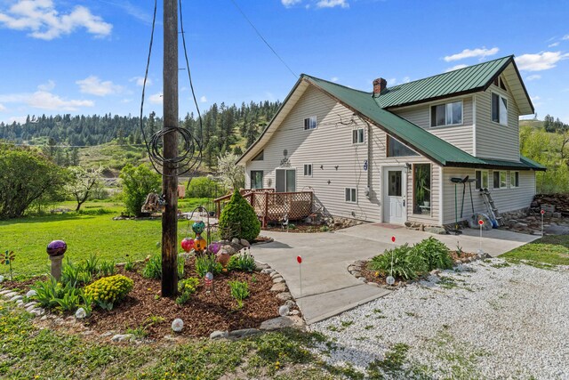 3063 Hungry Hill Rd, Kettle Falls, WA 99141 - rear view of house featuring a chimney, metal roof, a wooden deck, and a yard