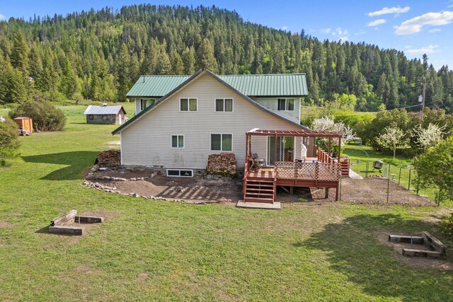 3063 Hungry Hill Rd, Kettle Falls, WA 99141 - rear view of house with a view of trees, a wooden deck, a lawn, and metal roof