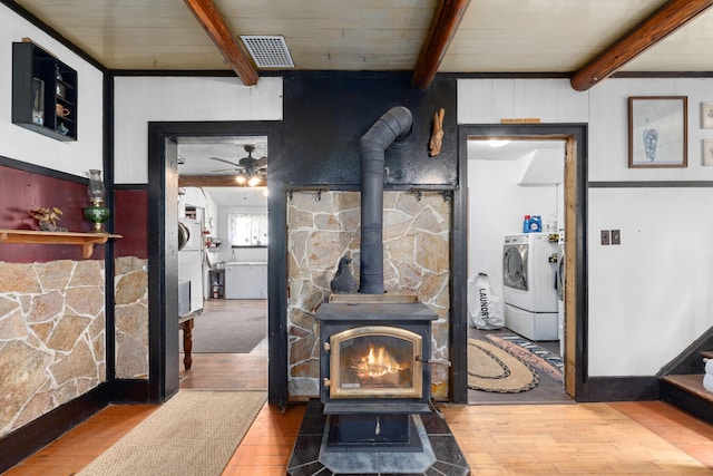 3063 Hungry Hill Rd, Kettle Falls, WA 99141 - living area featuring a wood stove, beamed ceiling, hardwood / wood-style flooring, ceiling fan, and washing machine and dryer
