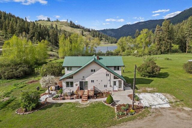 3063 Hungry Hill Rd, Kettle Falls, WA 99141 - back of house with a mountain view, a lawn, a wooded view, metal roof, and a patio area