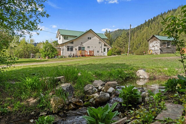3063 Hungry Hill Rd, Kettle Falls, WA 99141 - view of front facade with a front yard, metal roof, and a view of trees