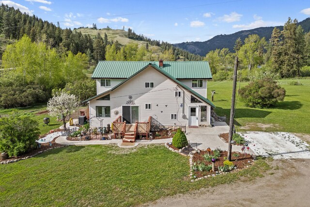3063 Hungry Hill Rd, Kettle Falls, WA 99141 - rear view of property featuring a deck with mountain view, a lawn, metal roof, and a chimney