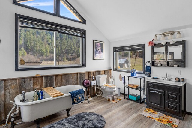 3063 Hungry Hill Rd, Kettle Falls, WA 99141 - bathroom featuring wood finished floors, vaulted ceiling, a soaking tub, vanity, and toilet