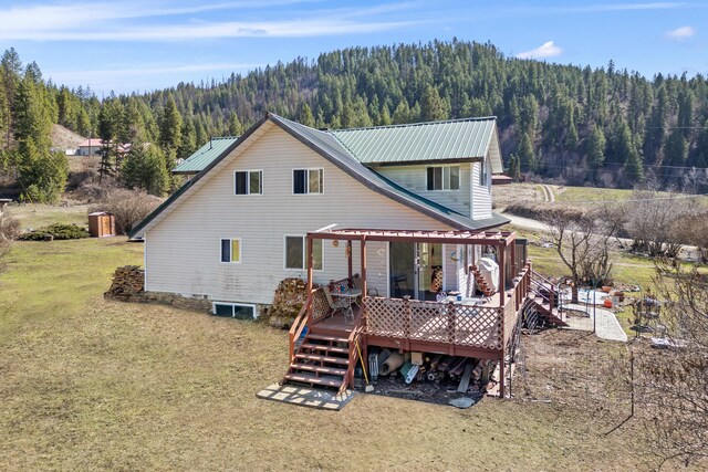 3063 Hungry Hill Rd, Kettle Falls, WA 99141 - rear view of property featuring a view of trees, metal roof, a yard, and a wooden deck