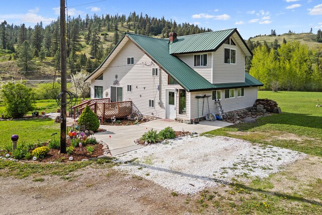 3063 Hungry Hill Rd, Kettle Falls, WA 99141 - back of property with a chimney, metal roof, a yard, a wooden deck, and driveway