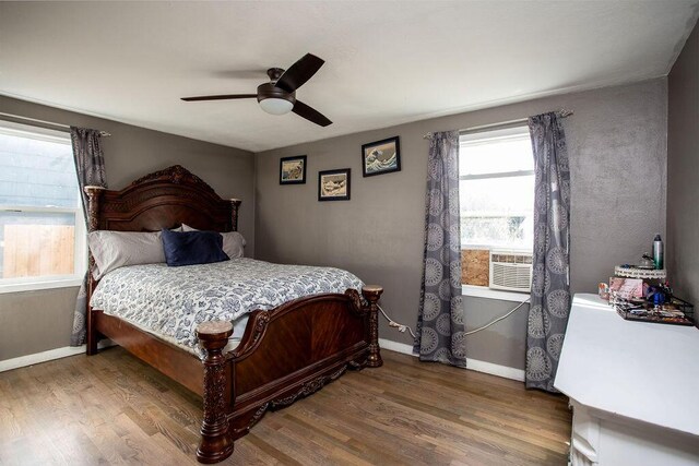 bedroom with ceiling fan, cooling unit, and wood-type flooring