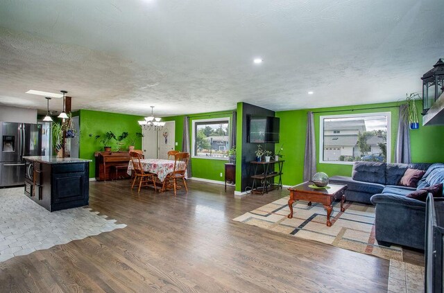 living room with a textured ceiling, hardwood / wood-style floors, and an inviting chandelier