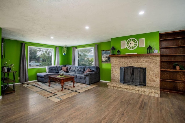 living room featuring a brick fireplace, hardwood / wood-style floors, and a textured ceiling