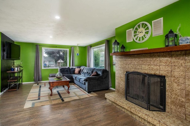 living room featuring a brick fireplace and dark hardwood / wood-style floors