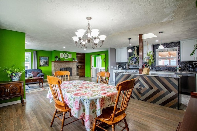 dining space featuring light hardwood / wood-style flooring, sink, a fireplace, a textured ceiling, and a chandelier